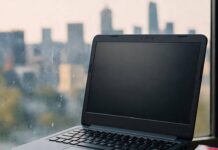 Best Budget Laptops in 2025: Top Picks for Affordable Performance Blurred laptop on coffee cups and notebook, city skyline, sock, cassette sticker.